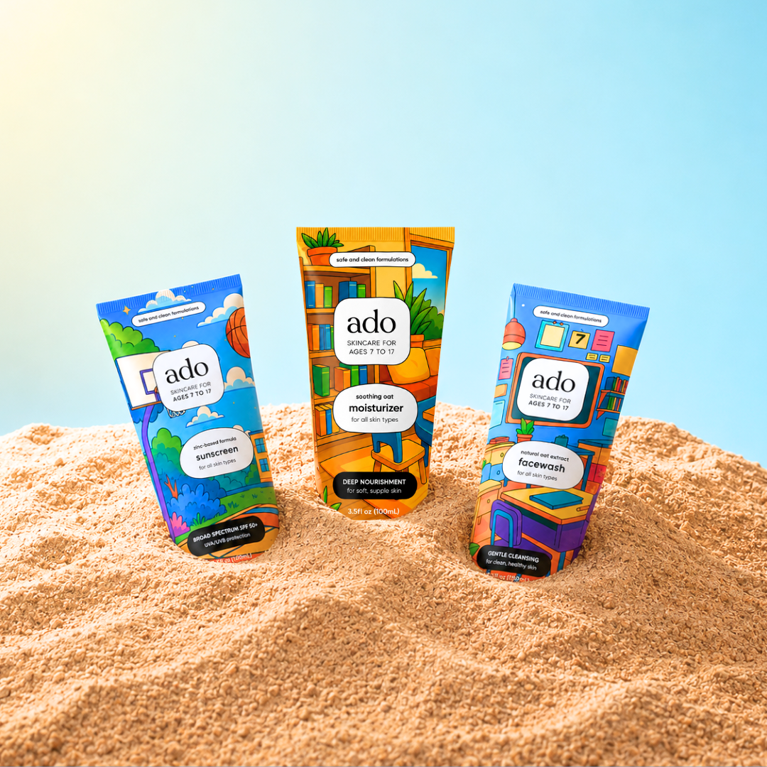 The ado sunscreen, moisturiser and facewash tubes half-buried in sand against a clear sky