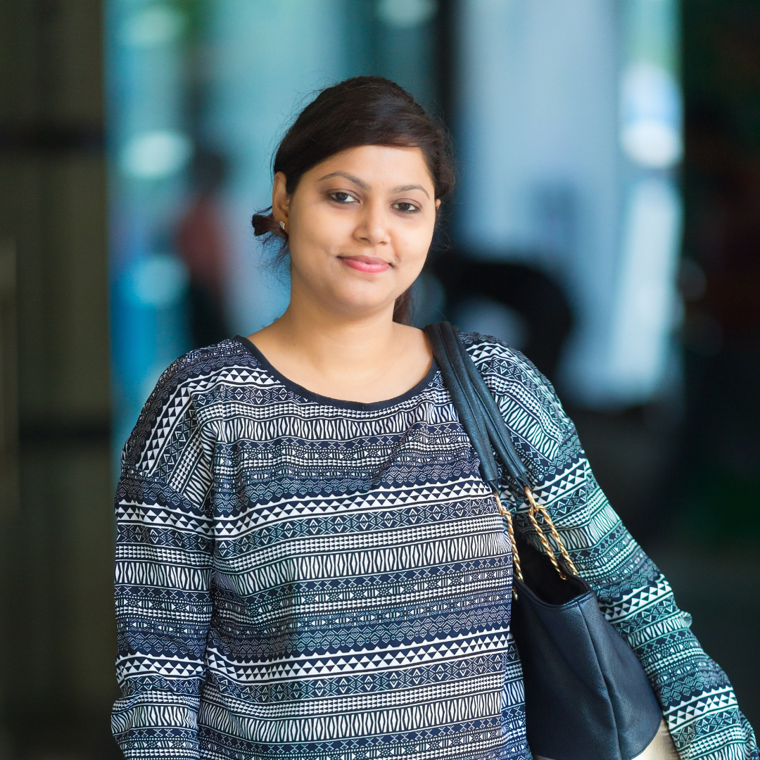 Woman in a patterned top with a shoulder bag, smiling softly