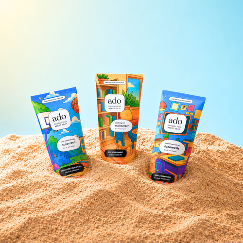 ado facewash, moisturiser and sunscreen tubes standing in sand on a sunny day